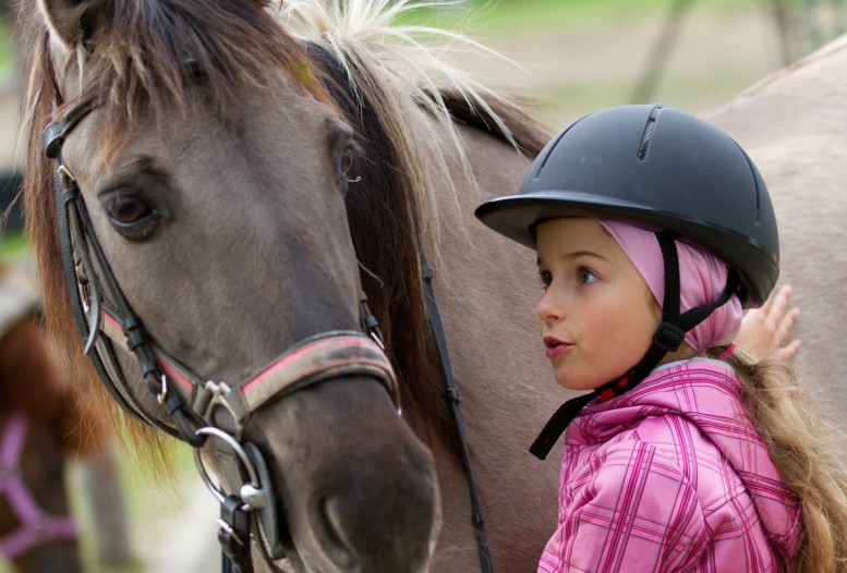 Mädchen vertraut mit Pferd beim Reiten